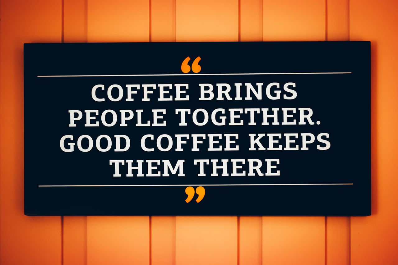 A motivational coffee quote displayed on a decorative sign.